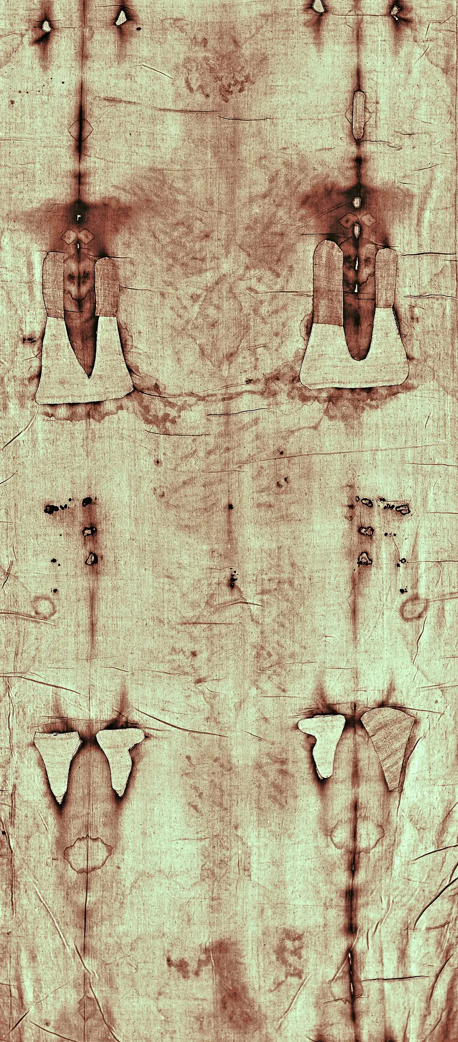 Die Rückseite des Mannes auf dem Grabtuch, blass bräunlich auf hellem Leinen, beiderseits begrenzt von dunklen Brandlinien und hellen Flicken des Brandes von 1532.